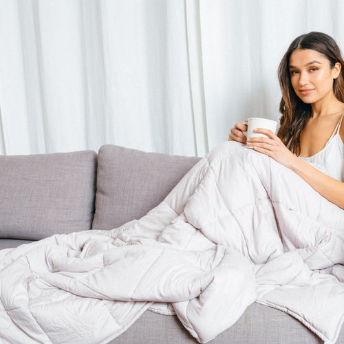 woman under weighted blanket with coffee